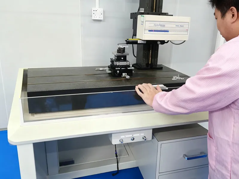 A quality control technician at the factory using a precision coordinate measuring machine (CMM) or profilometer to verify the dimensional accuracy and surface profile of injection-molded lenses.