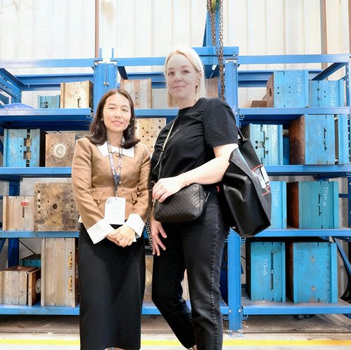 A technical consultation session with an overseas client in the mold storage area, featuring heavy-duty racking systems filled with precision tooling inserts and mold bases for active projects.