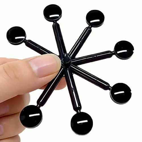A hand holding a circular black plastic array of multiple sensor lenses, which are connected by molding runners, over a white background.