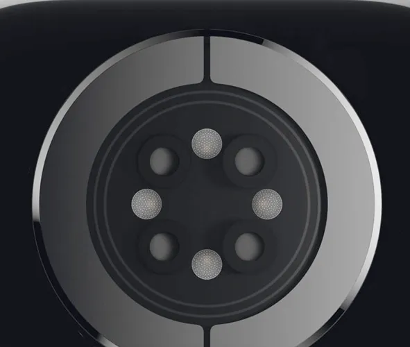 A close-up view of a circular PPG optical pulse oximeter sensor lens for smartwatches and wearable medical devices. The module features an outer metallic electrode ring surrounding a dark optical window, which integrates a multi-channel cluster of micro-structured LED lenses and photodiode apertures, demonstrating high-precision optical molding and anti-crosstalk isolation design.