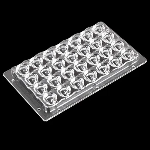 A clear 24-in-1 multi-LED street light optical lens array board on a black background. Made of optical-grade PC/PMMA via precision injection molding, the lens module features asymmetric freeform batwing optical designs with perimeter mounting holes, engineered for uniform road illumination and high light transmission in LED street luminaires.